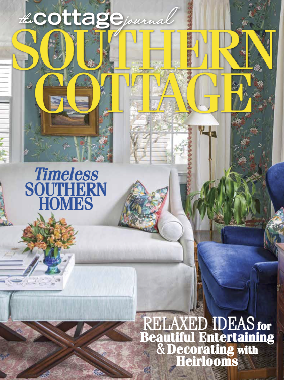 Cover of Southern Cottage magazine featuring a cozy living room with floral wallpaper, a white sofa with colorful cushions, a blue armchair, a coffee table with a flower arrangement, and a window with curtains.